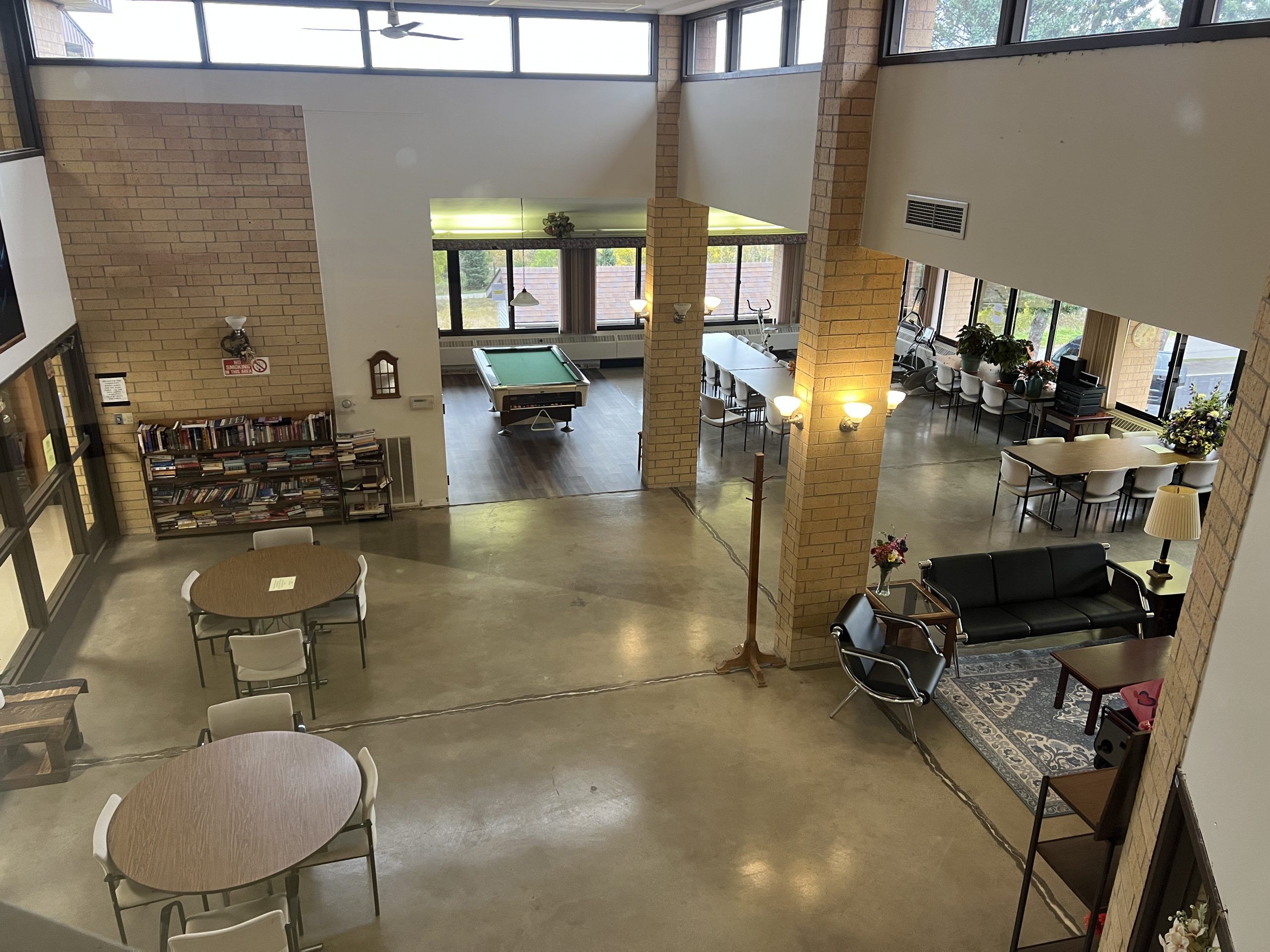View of common area in Pleasant Valley Apartments with books, pool table, tables and chairs.